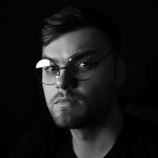 Portrait of a person wearing glasses against a dark background