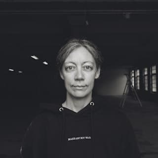 Portrait of a person in a dark hooded top, looking at the camera